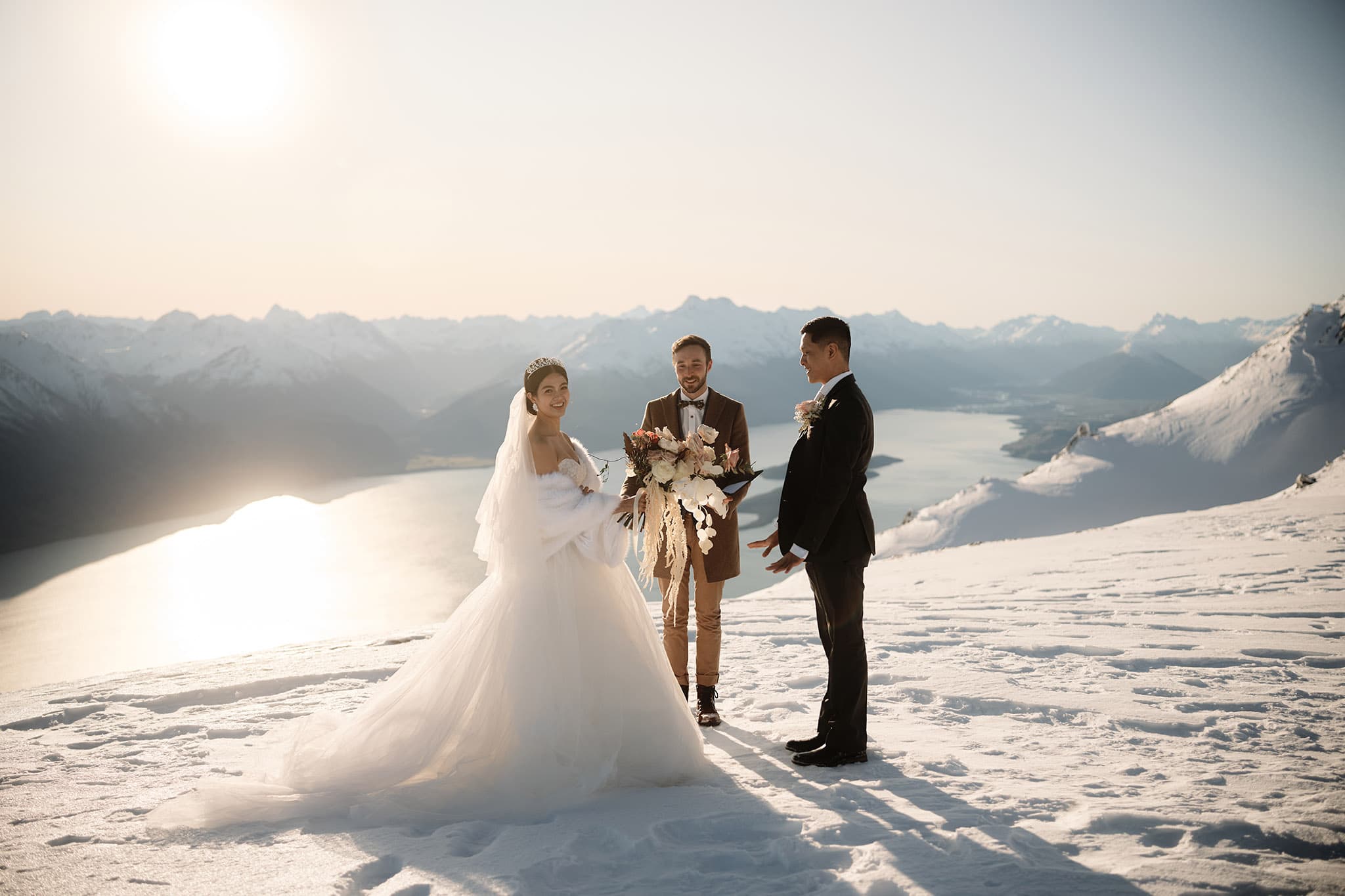 クイーンズタウン　ニュージーランド　ウェディング　前撮り　挙式　結婚式　フォトグラファー | 雪山の頂上でクイーンズタウンのヘリウェディングを楽しむ新郎新婦。